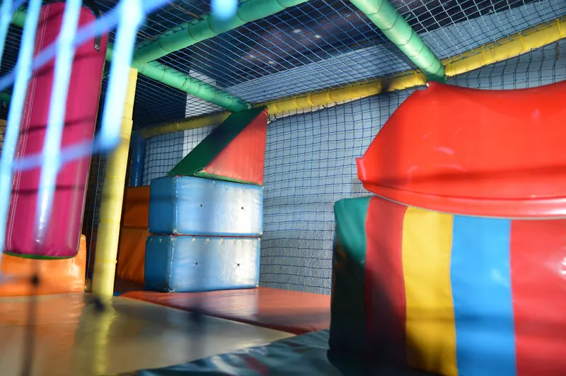 Bloques de espuma y cojines de colores dentro de la estructura de juego techada con red