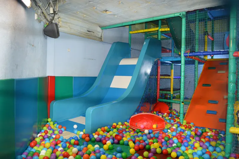 Tobogán con pared de escalada naranja y piscina de bolas en una de las zonas de juego de FlipoPark