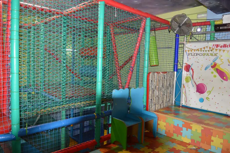 Vista general del escenario de cumpleaños con sillas infantiles y tarima de puzle junto a la red de juego
